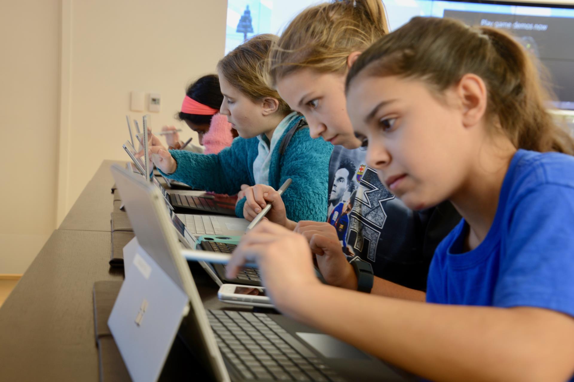 Five middle school students working on touchscreen laptops